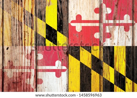 Maryland US state national flag on a gray wooden boards background on the day of independence in different colors of blue red and yellow. Political and religious disputes, customs and delivery.