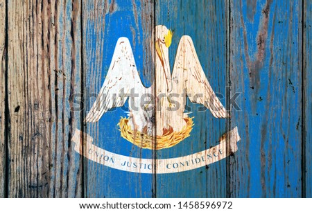Louisiana US state national flag on a gray wooden boards background on the day of independence in different colors of blue red and yellow. Political and religious disputes, customs and delivery.