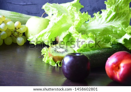 Assortment of fresh fruits and vegetables. Green fruits and vegetables on a black background. Kiwi, green grapes, lettuce, zucchini, cucumbers, green apple, parsley