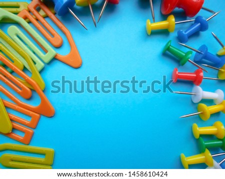 Multicolored latch clips scattered across a turquoise background. View from above. The concept is time to school.