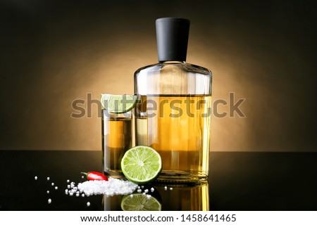 Tasty tequila with lime, salt and chili pepper on dark background Royalty-Free Stock Photo #1458641465