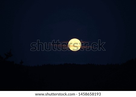Very bright full moon rising over a ridgeline in Oregon.