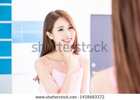 Beauty skin care woman touch her chin and smile in front of mirror
