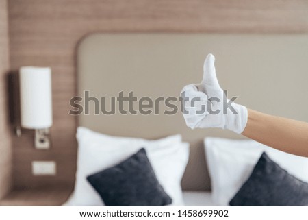 partial view of maid in white glove showing thumb up in hotel room