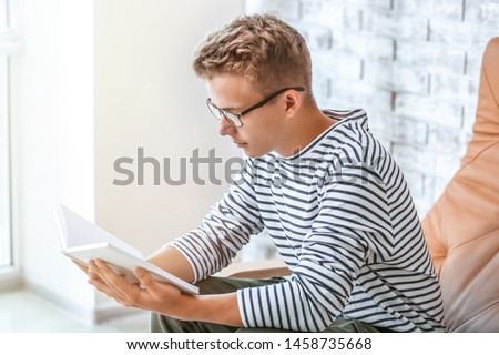 Male student reading book while preparing for exam
