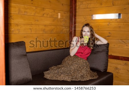 Scandinavian design style with an emphasis on simple, minimalist decor. A beautiful girl in a dress sits on a couch covered with a warm blanket with a mug of tea 