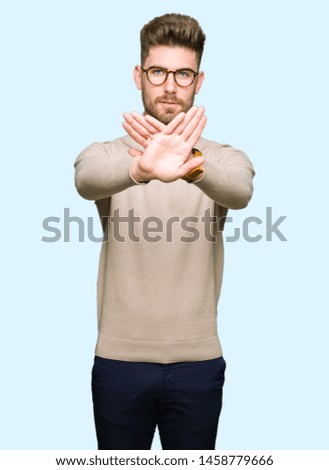 Young handsome business man wearing glasses Rejection expression crossing arms and palms doing negative sign, angry face