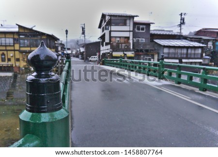 Wet black bridgehead of Yanagibashi bridge with blurred background on snowy morning in Takayama Japan