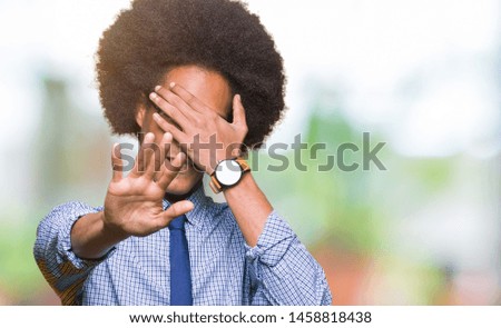 Young african american business man with afro hair wearing glasses covering eyes with hands and doing stop gesture with sad and fear expression. Embarrassed and negative concept.