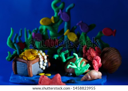 Plasticine underwater landscape. The ocean and the undersea world background, corals and open pirate chest with shinny gold.