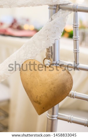 Gold tin heart decor on chair at wedding reception