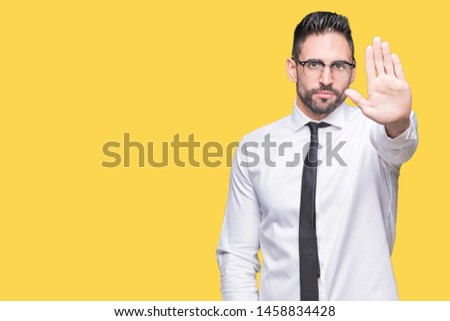 Young handsome business man wearing glasses over isolated background doing stop sing with palm of the hand. Warning expression with negative and serious gesture on the face.