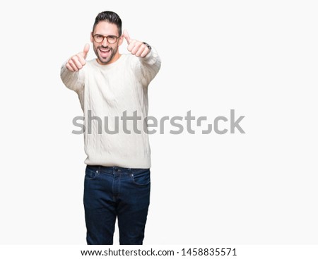 Young handsome man wearing glasses over isolated background approving doing positive gesture with hand, thumbs up smiling and happy for success. Looking at the camera, winner gesture.