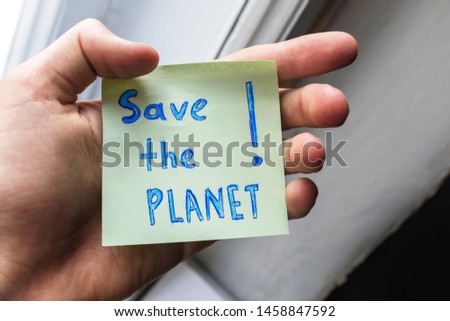 an appeal to save the planet earth is written on a piece of paper. handwritten inscription save the planet on a square piece of paper in the male hand. Save planet, environment care concept
