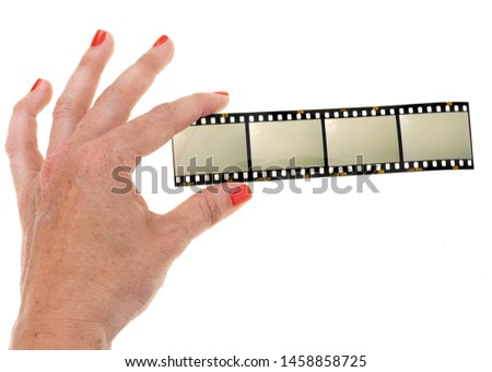 left female hand holding 35mm film strip with empty film cells on white background, blank frames or photo placeholder on film material