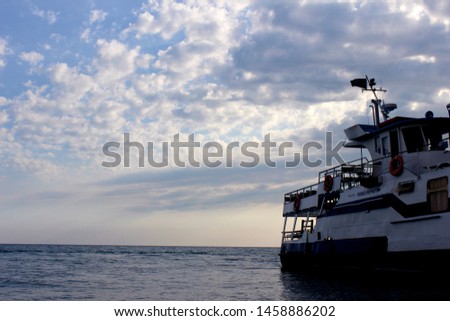 ship boat marine transportation with a flag on the background of the sea and sunset cloudy sky