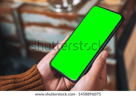 Mockup image of hands holding black mobile phone with blank desktop screen 