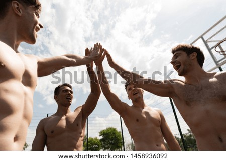 laughing shirtless sportsmen touching hands at basketball court