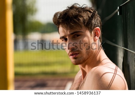 serious shirtless young man at basketball court looking at camera