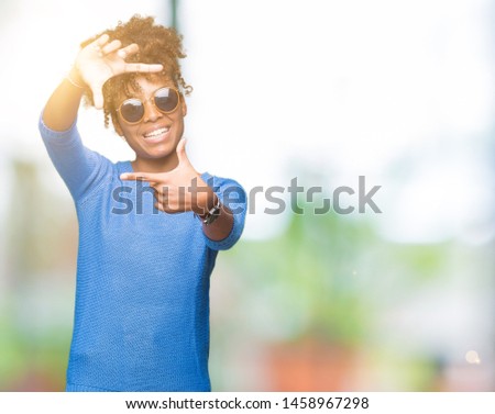 Beautiful young african american woman wearing sunglasses over isolated background smiling making frame with hands and fingers with happy face. Creativity and photography concept.