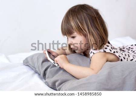 Girl hold telephone in hand and playing smartphone watching cartoons at home. european child 2-3 year old Kids addicted to games problems of children use smartphone technology.The joy of missing out 