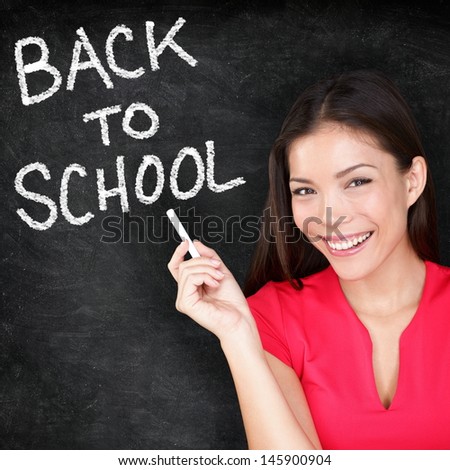 Back to school - woman teacher smiling by blackboard. Female teaching writing BACK TO SCHOOL on chalkboard. Young female primary school teacher or Asian university student going back to college.