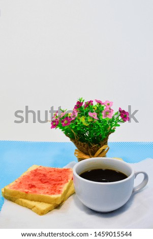 Bread topped with jam and a cup of coffee, placed beside from a bouquet of flowers