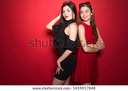 Two woman ready for girls party prom night main theme of weekend wear festive dresses on red background