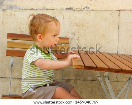 little boy with blond hair sits at a wooden table