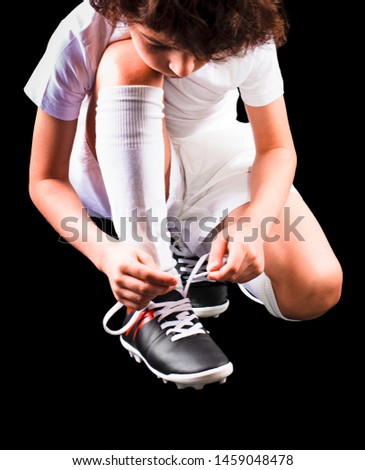 Little boy football player in boots puts lace on black background