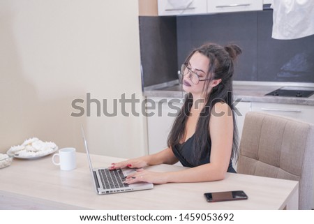 cute girl with glasses sitting at the table with a laptop at home alone
