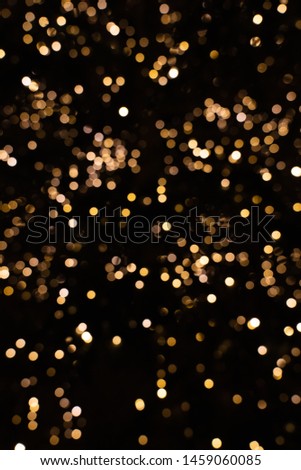 Blurry golden and white fairy lights in dark night creating beautiful bokeh effect with glowing circles or shiny dots, abstract image for Christmas or holiday card, banner or background