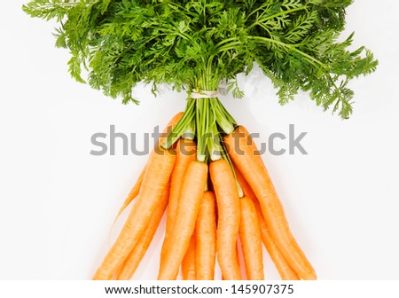 Healthy and brightly colored bunch of crop of organic carrots with green leaves isolated on a clean white background.