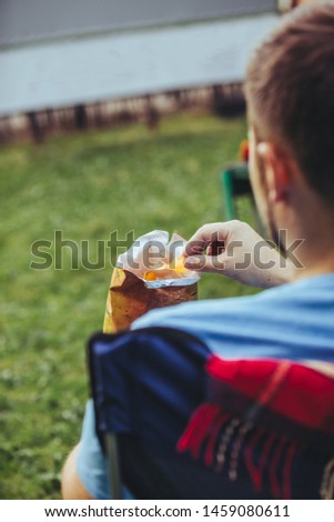 man sitting in camp-chair drink beer eat snacks watching movie in city park open air cinema concept