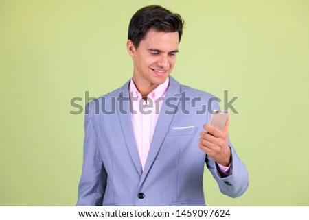 Portrait of happy young handsome businessman using phone