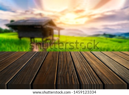 Brown wood table in summer farm green landscape with empty copy space on the table for product display mockup. Agriculture and outdoors picnic concept.
