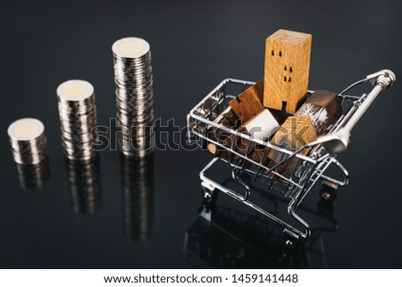 Wood house from in cart on dark table with row of coin money selective focus, Planning to buy property. Choose what's the best. A symbol for construction ,ecology, loan concepts