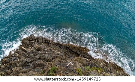 Top eye view of ocean scene with wave hitting a rock