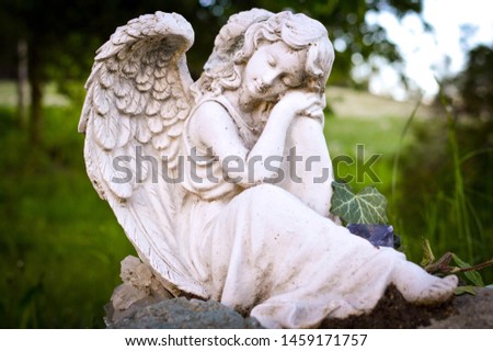 statue of a female angel with closed eyes in a cemetery on a gravestone;
