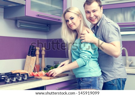 Happy family concept. Portrait of a romantic couple (husband and wife) standing together in their new kitchen room and preparing breakfast. Woman is pregnant. Healthy food. Indoor shot
