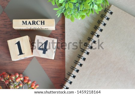 March 14. Date of March month. Number Cube with a flower and notebook on Diamond wood table for the background.