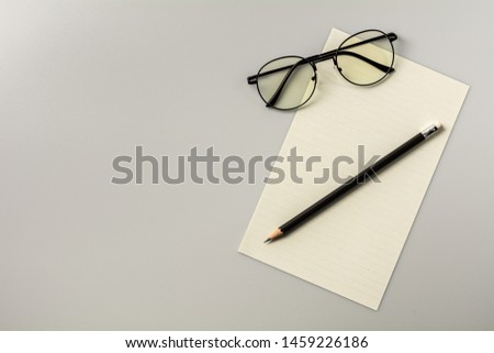 blank note paper and a pencil on grey desk background.