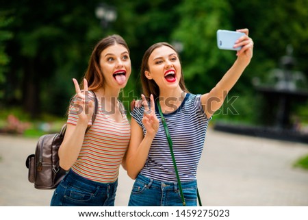 Portrait of funny youth with red brunette hair pomade make photos v-signs fool wear backpack rucksack striped t-shirt denim jeans in town outdoors
