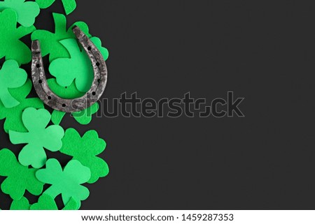 Green clover sheets and old rusty horseshoe on a dark background top view. Blank, template, postcard to the day of St. Patrick with a place for text.