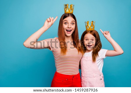 Excited foxy little lady and mommy indicating fingers on tiara wear casual outfit isolated blue background