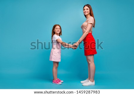 Photo of foxy little lady and mom holding hands standing opposite wear casual clothes isolated blue background