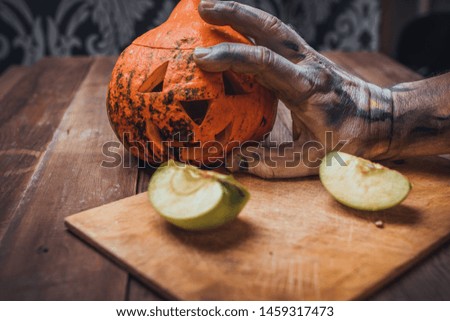 zombie hand cuts a lantern from a pumpkin for the celebration of Halloween