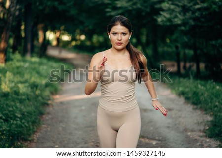 A young woman runner runs  in a park in the park.