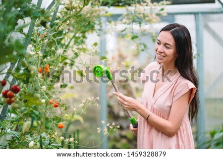 Young happy woman watering their crops in the greenhouse