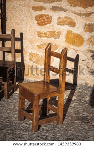OLD WOODEN CHAIR AND STONE WALL IN THE VILLA OF SEGOVIA IN SPAIN